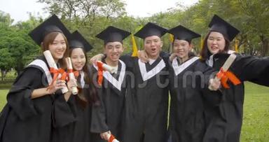 在大学校园里穿毕业礼服拿毕业证书的快乐学生